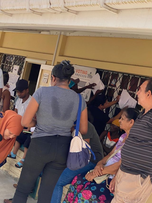 Residents in line to vote while others check for their names on the voter's list