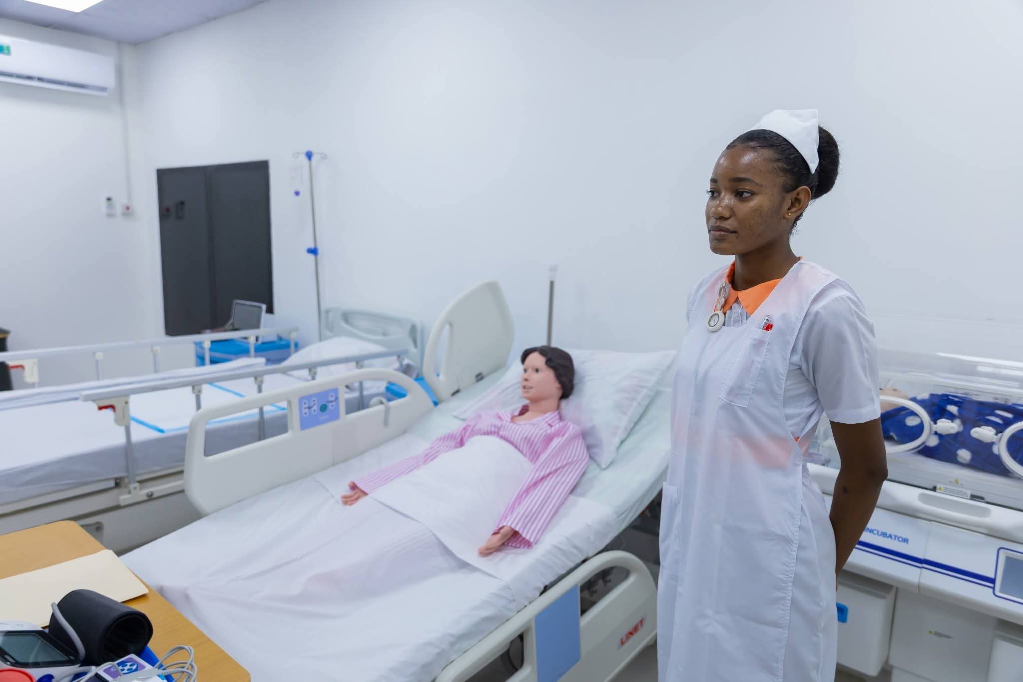 A nurse stands next to a dummy in the simulation centre